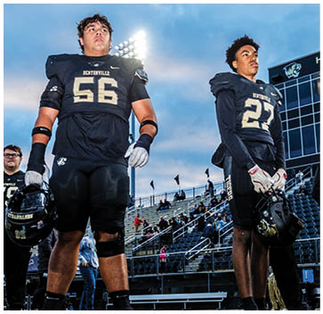 A group of football players standing on a field. Description generated by AI