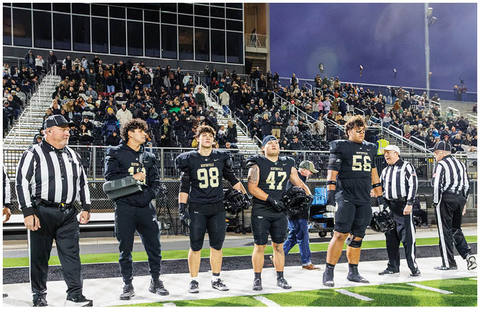 A group of football players standing on a field. Description generated by AI