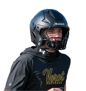 A person wearing a black football helmet and a black shirt with yellow text that reads “Verot Football" is holding black gloves and appears to be on a sports field. Descripci n generada con IA