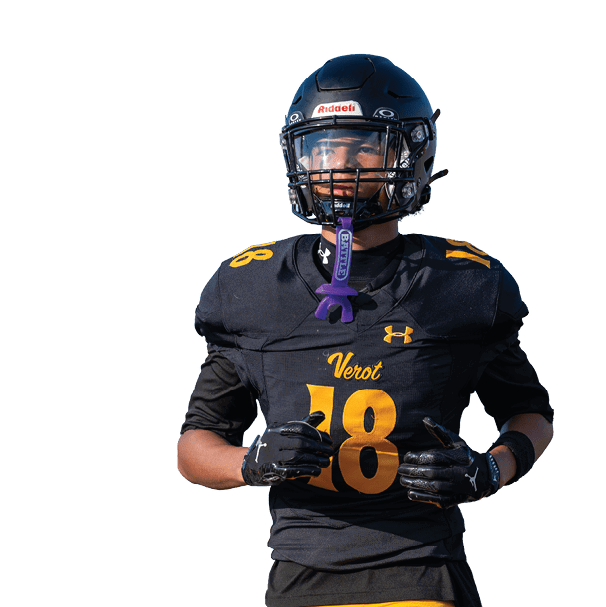 A person wearing a black football uniform with the number 18 and a helmet is standing with hands near the chest. Descripci n generada con IA