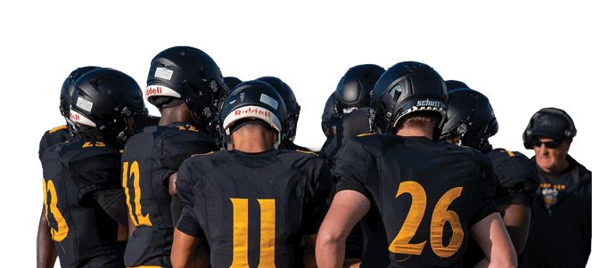 A group of people wearing black helmets and black and yellow sports uniforms are huddled together on a field with one person standing nearby. Descripci n generada con IA