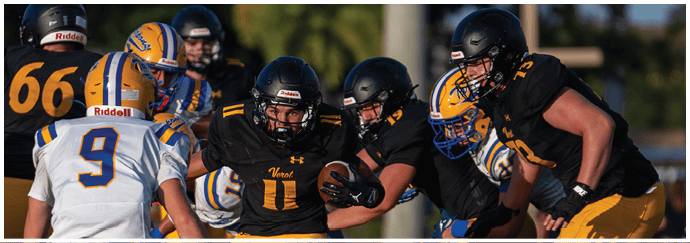 Adults wearing football helmets and uniforms are engaged in a play on a grassy field with one player holding the ball while others prepare to block or tackle. Descripci n generada con IA