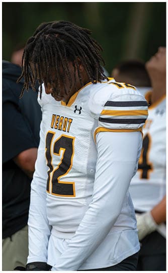 A person with dreadlocks wearing a white football jersey with the number 17 and the word “VEROT" is looking downward. Descripci n generada con IA