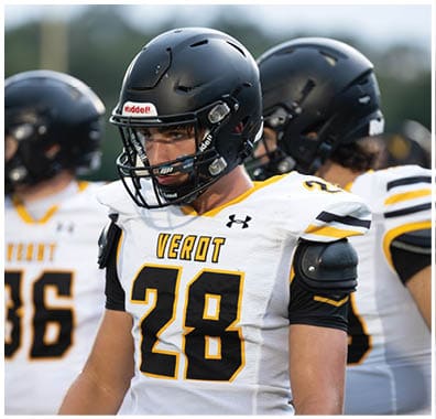 Three people wearing black football helmets and white jerseys with black and yellow accents stand together on a field. Descripci n generada con IA