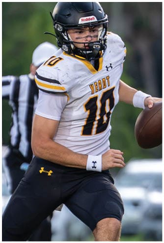 A person wearing a football uniform with the number 10 is running on a grassy field while holding a football, with a referee visible in the background. Descripci n generada con IA