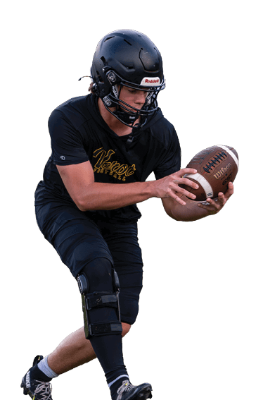 A person wearing a black helmet and sports gear is holding a football and appears to be preparing to pass or hand it off on a grassy field near a yard marker. Descripci n generada con IA