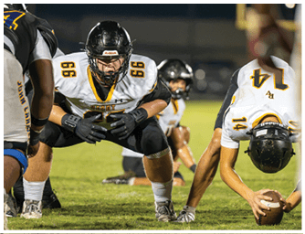 People in football uniforms are positioned on a grassy field preparing for a play during a game. Descripci n generada con IA