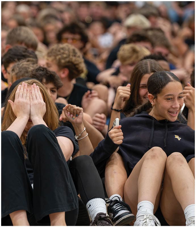 A group of people sitting closely together with one person in front covering their face with their hands while others around them show various hand gestures and expressions. Descripci n generada con IA