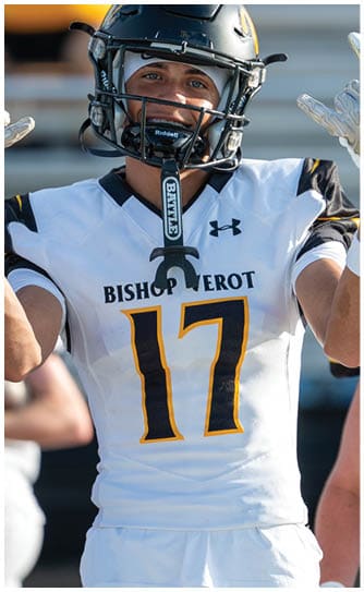 A person wearing a black football helmet and a white Bishop Verot jersey with the number 17 is raising their arms. Descripci n generada con IA