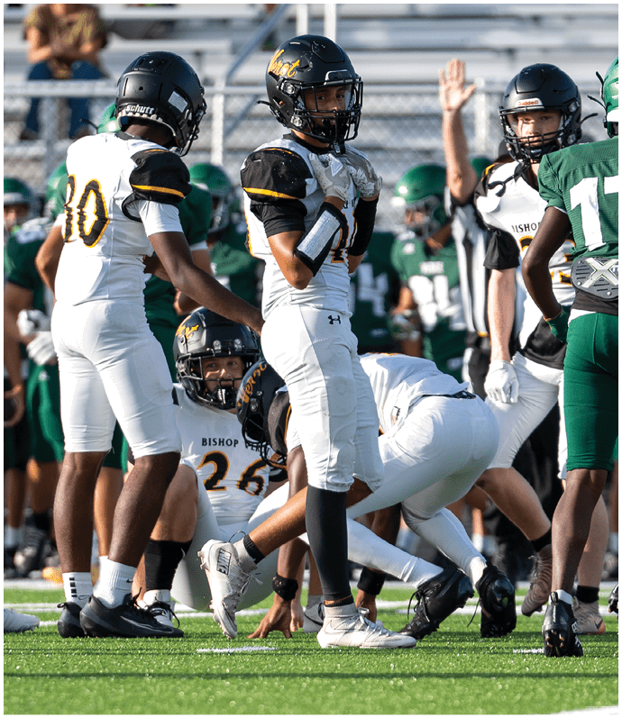 Several people wearing football uniforms and helmets are gathered on a field with one person in green facing away and others in white standing or crouching nearby. Descripci n generada con IA