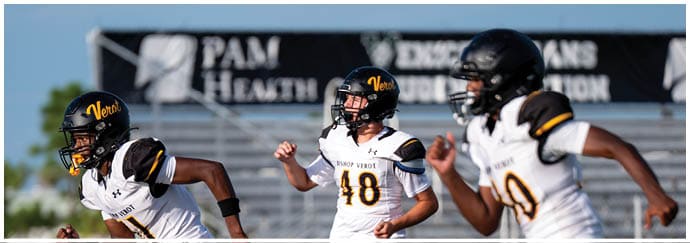 Two people wearing black helmets and sports gear are engaged in an outdoor activity with a blurred banner in the background. Descripci n generada con IA