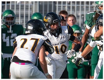 Three people in football uniforms with helmets are actively engaged in a game on a field with others in the background. Descripci n generada con IA