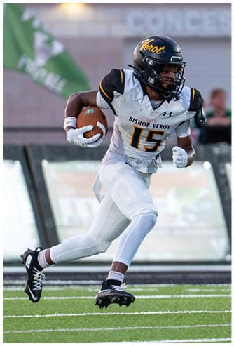 A person wearing a football uniform with the number 15 is running on a field while holding a football. Descripci n generada con IA