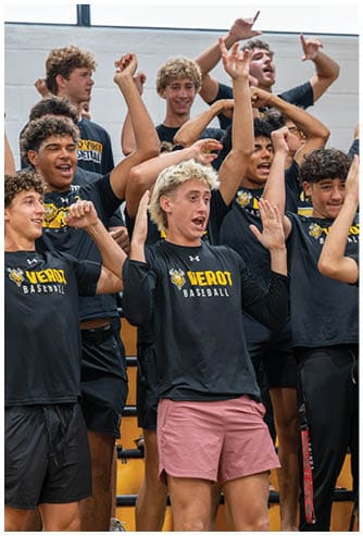 A group of people wearing matching sports shirts enthusiastically raise their arms and cheer inside a gymnasium. Descripci n generada con IA