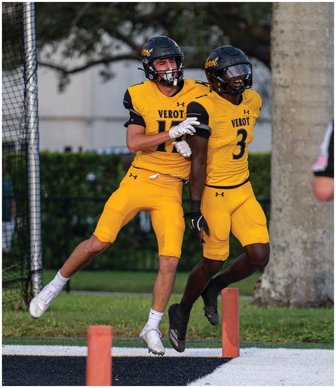 Two people in yellow football uniforms jump and celebrate near the end zone on a football field. Descripci n generada con IA