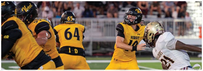 A group of people in yellow and black football uniforms are playing on a field while a person in white and gold uniform is falling or being tackled. Descripci n generada con IA