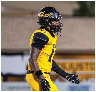 A person wearing a yellow and black football uniform and helmet is walking on a football field. Descripci n generada con IA