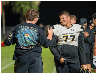 Three people in football uniforms with helmets are actively engaged in a game on a field with others in the background. Descripci n generada con IA