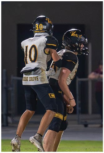 A person wearing a football uniform with the number 15 is running on a field while holding a football. Descripci n generada con IA