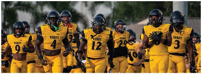 A group of people wearing yellow sports uniforms with helmets are running together on a field. Descripci n generada con IA