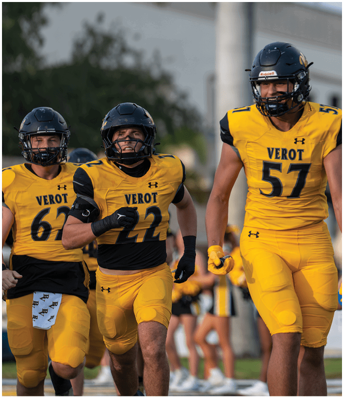 Three people wearing yellow and black football uniforms with helmets are running on a field with blurred spectators in the background. Descripci n generada con IA