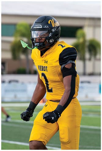 A person in a yellow and black football uniform with the number 2 is standing on a field with a determined expression and clenched fists. Descripci n generada con IA