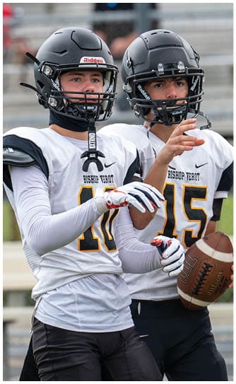 A person wearing a black football helmet and a white Bishop Verot jersey with the number 17 is raising their arms. Descripci n generada con IA