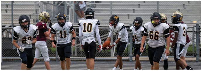 Two people wearing black helmets and sports gear are engaged in an outdoor activity with a blurred banner in the background. Descripci n generada con IA