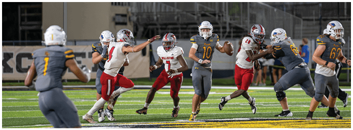 A group of people in yellow and black sports uniforms are playing football on a field with one person on the ground and others running or preparing to move. Descripci n generada con IA