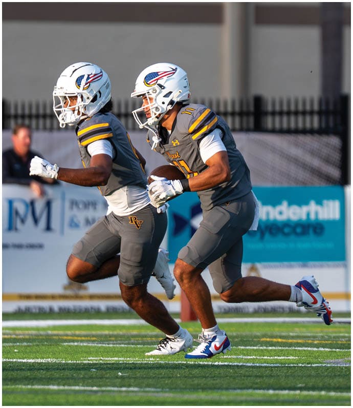 Two people in yellow football uniforms jump and celebrate near the end zone on a football field. Descripci n generada con IA
