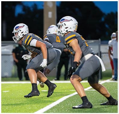 A person wearing a yellow and black football uniform and helmet is walking on a football field. Descripci n generada con IA