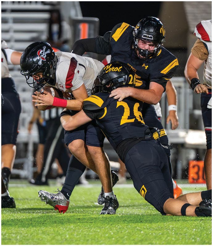 Three people in football uniforms and helmets are engaged in a tackle during a game on a grassy field. Descripci n generada con IA