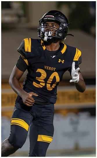 A person wearing a black and yellow football uniform with the number 30 and a helmet is running on a field. Descripci n generada con IA