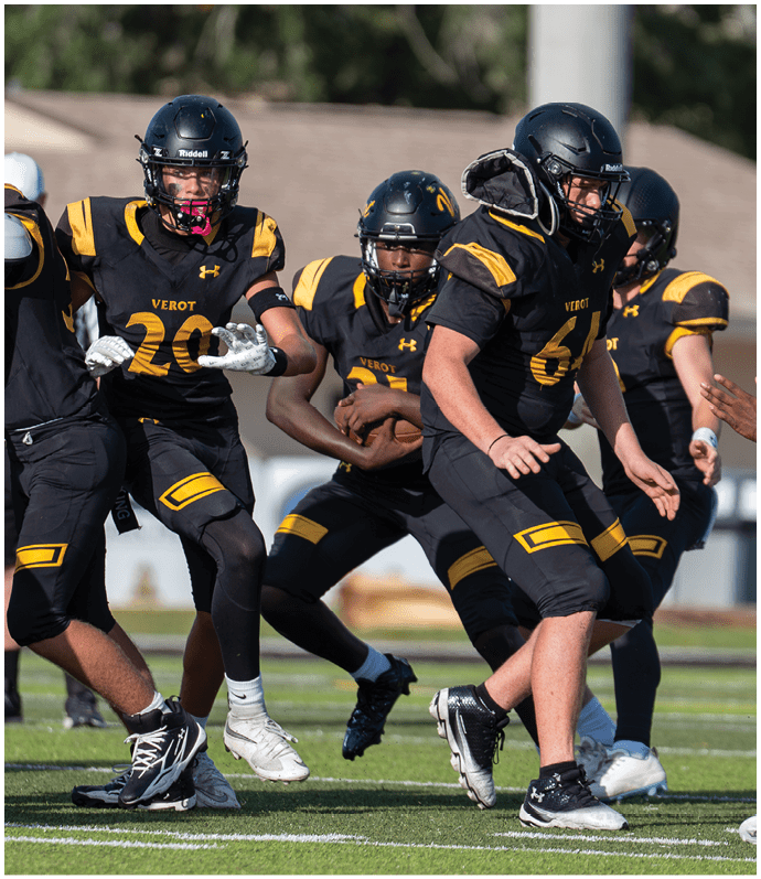 Several people wearing black and yellow football uniforms and helmets are actively engaged in a play on a grassy field. Descripci n generada con IA