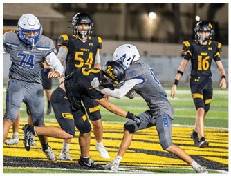 Four people in football uniforms are engaged in a play on a field with a large yellow and black logo at the center. Descripci n generada con IA