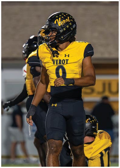 A person wearing a yellow football jersey with the name “VEROT" and the number zero is shown in profile wearing a black helmet decorated with small skull and crossbones. Descripci n generada con IA