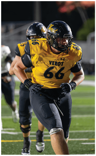 An adult wearing a yellow and black football uniform with the number 66 is running on a football field during a game. Descripci n generada con IA