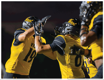 Two people wearing yellow and black football uniforms and helmets are giving each other a high five during a game. Descripci n generada con IA