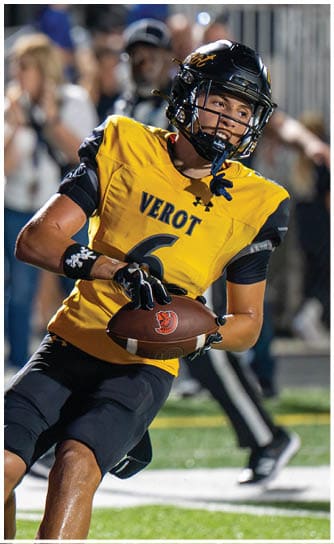 A person wearing a yellow football jersey with the word “VEROT" and the number six is holding a football and appears to be preparing to throw it during a game. Descripci n generada con IA