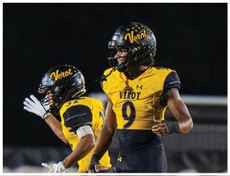 Two people wearing yellow and black football uniforms with helmets are on a field, appearing to be in action during a game. Descripci n generada con IA