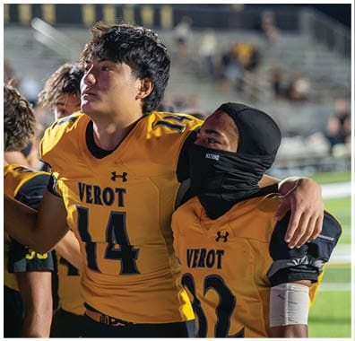 People wearing yellow and black football uniforms with the word “VEROT" and numbers on the jerseys are standing closely together. Descripci n generada con IA