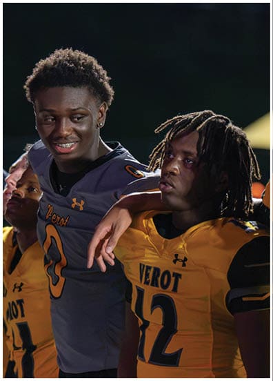 Three people wearing football jerseys with the word “Verot" stand closely together, with one person in a gray jersey smiling and resting an arm on the shoulder of another person in a yellow jersey. Descripci n generada con IA