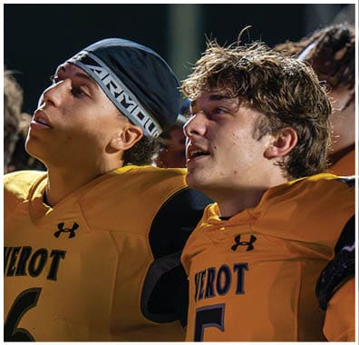 Two people wearing yellow sports jerseys with the word “VEROT" are standing close together, one with curly hair and the other wearing a black headband with white text. Descripci n generada con IA