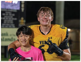 Two people are smiling, one wearing a yellow sports jersey with wet hair, and the other partially visible with dark hair. Descripci n generada con IA