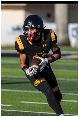 A person wearing a black and yellow football uniform and helmet is running on a football field while holding a football. Descripci n generada con IA