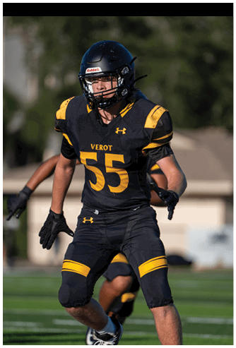 A person wearing a black and yellow football uniform with the number 55 is running on a football field during a game. Descripci n generada con IA