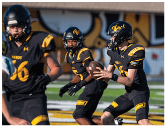 Three people in black and yellow football uniforms are on a field with one person holding a football preparing to pass it. Descripci n generada con IA