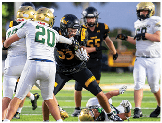 A group of people in football uniforms are engaged in a play on a field with one person in black and yellow running with the ball while others in white and gold attempt to tackle or block. Descripci n generada con IA