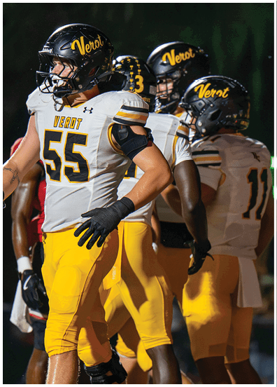 A person wearing a white and yellow football uniform with the number 55 and the word Verot on the jersey and helmet is standing with hands on hips. Descripci n generada con IA