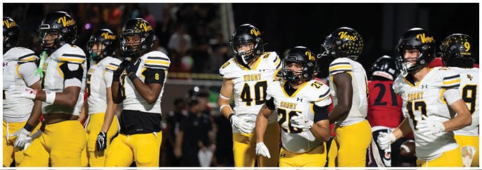 Several people wearing yellow football uniforms with black and white accents stand on a field during a game. Descripci n generada con IA